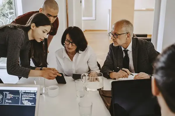 Två män och två kvinnor i olika åldrar arbetar tillsammans vid ett konferensbord.